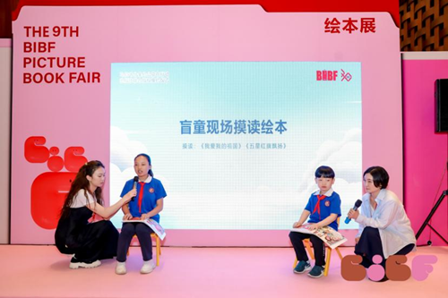 图为盲童朗读大字盲文对照绘本《我爱我的祖国》《五星红旗飘扬》