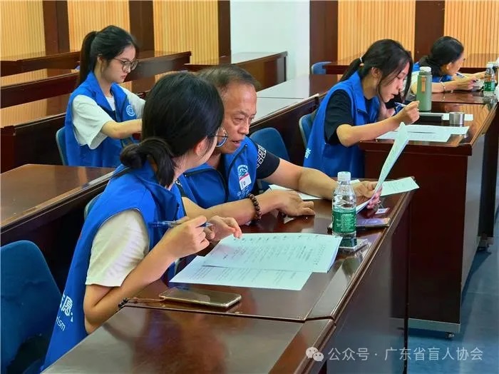 图为志愿者协助视障选手答题